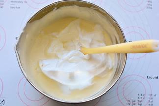 然后将混合好的面糊全部倒入剩余的蛋白霜里，刮刀画Z字形快速翻拌均匀。