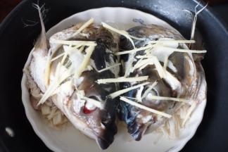 金针菇蒸软后放入鱼头，在鱼头表面铺上姜丝，盖上锅盖蒸8分钟