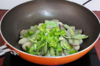 把青辣椒，洗净切块，加入锅里翻炒；并加一碗水，盖上盖子，大火煮沸，转为中火焖。
