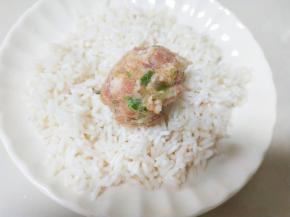 用手取适量馅团成圆形，放入大米中滚几下。