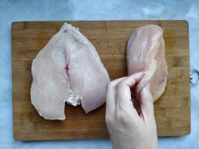 将整块鸡胸肉从一边横向剖开，另一边不要切断，形成如图的样子。