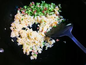 将午餐肉黄瓜丁推到锅一边，放入裹上蛋液的米饭翻炒至熟散开
