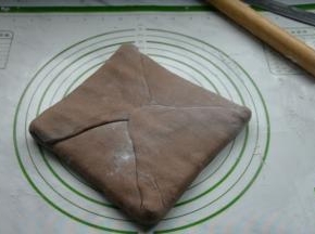 将面片四角向中间折叠，裹住黄油片，捏紧边缘。