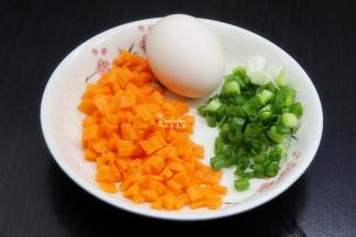 在等待蒸饭的过程，把胡萝卜去皮切粒、香葱洗净切好；