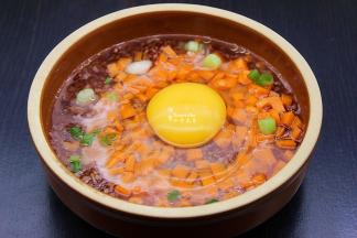 在烹饪倒计时12分钟时，打开蒸烤箱的门，取出红米饭，铺上一层胡萝卜粒，少许葱，打入鸡蛋在中间，放一点油