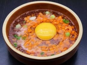 在烹饪倒计时12分钟时，打开蒸烤箱的门，取出红米饭，铺上一层胡萝卜粒，少许葱，打入鸡蛋在中间，放一点油