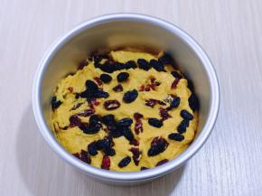 将6寸活底蛋糕模具刷上一层食用油（以便脱模）取一半拌好的南瓜面糊放入模具中，抹平，撒上洗干净的黑加仑干与蔓越莓干！