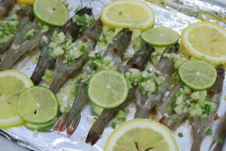 用刀面轻拍虾肉，放入烤盘，铺上柠檬片，放上蒜泥茸