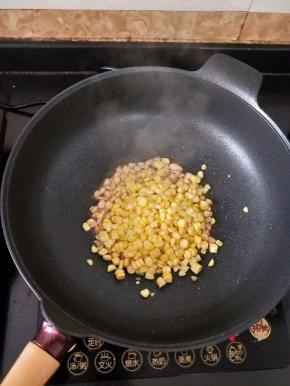 然后放入玉米粒，翻炒均匀。