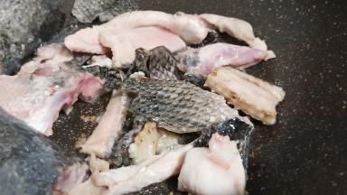 锅里加适量的油、放生姜片、蒜翻炒出香味、加鱼骨煎至两面微黄。