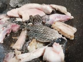 锅里加适量的油、放生姜片、蒜翻炒出香味、加鱼骨煎至两面微黄。