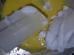 取二分之一蛋白放入蛋黄糊中，用刮刀翻拌均匀(不可画圈搅拌)