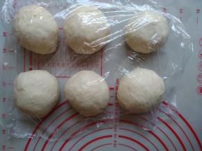 将面团取出，分成6份，轻压排气，滚圆后盖上保鲜膜，松驰15分钟