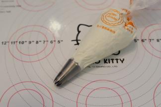 裱花袋装好8齿裱花嘴，淡奶油加入细砂糖，打发至裱花状态，装入裱花袋内。