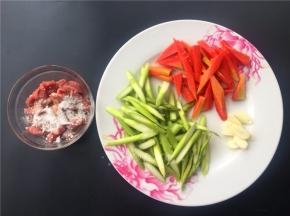 将芦笋和胡萝卜切成如图所示，大蒜切片，牛肉切条加适量淀粉拌匀。