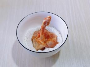 首先将腌制好的鸡锤放入淀粉碗中，均匀裹上淀粉！