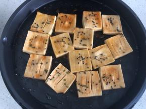 撒上芝麻，淋上刚才的调料汤汁，盖上约3分钟后打开翻面重复这个步骤，直到豆腐收汁即可