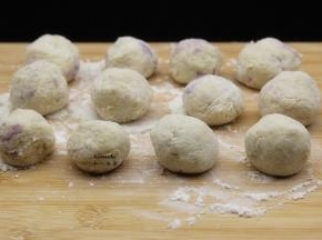 揉成光滑的土豆紫薯丸子；.做好的土豆紫薯丸子，撒一点裹炸粉上面