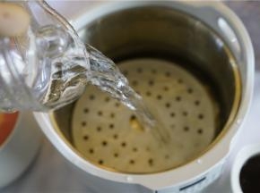 然后在炖锅里放入蒸垫，再加入清水，有指定的水位，不可少也不可多。将二个小炖盅移至到炖锅里面。