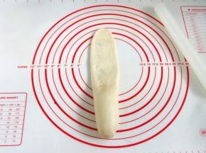 用擀面杖从面团的中间往上擀开。
