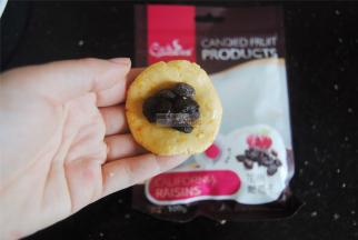 南瓜团子分成8小份，取一个揉圆捏扁，放上适量的加州葡萄干，不要要过量，太多会造成凹凸不平。