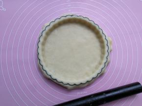 将面片盖在派盘里，面片贴合模具整理压实后，用擀面杖擀一圈派盘边沿，去掉多余面团