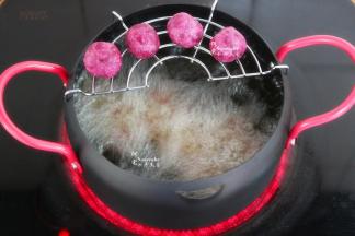 把紫薯丸子炸至外皮焦脆，酥香。捞出，放在沥油架上，继续炸第二锅。