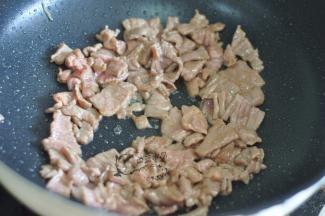 锅里倒入油，倒入牛肉片炒至变色。