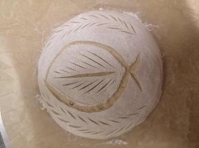 烤箱预热到250度 把面团扣到油纸上 撒粉 割包 割什么图案 就是你喜欢了 本来割包的来历 也是为了区分各家的面包 做的自己的标记 你的面包 你做主 进烤箱 喷蒸汽 没有 可以用土办法 扣个盆 