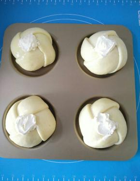 面团发酵两倍大，取出表面刷蛋液，中心凹的部分用勺子涂抹奶酪馅。