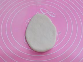 开始做圣诞老人的头部、取一块白色面团揉匀擀成上窄下宽的椭圆形，放旁边备用！