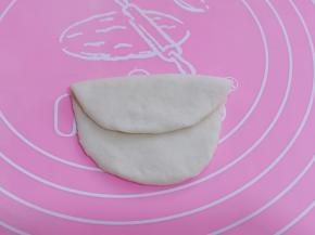 另取一块面团揉圆、擀成椭圆形后对折、不要对折的太齐、如图