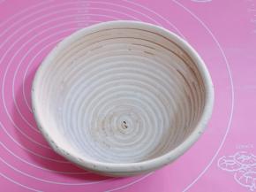 在发酵藤篮中倒入面粉，转动藤篮，让面粉均匀的粘在藤篮上。