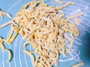 然后用刀切成长条片状，再改切成条状，并抖开防止粘连