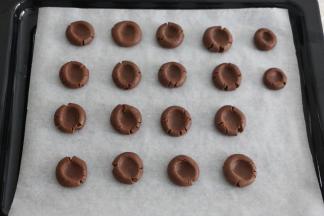 烤盘铺油纸，用大拇指轻轻将每个面团按扁。