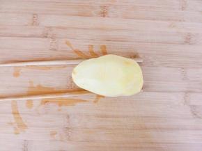 土豆洗净去皮，底下两边各垫一根筷子。