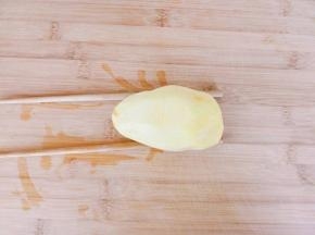 土豆洗净去皮，底下两边各垫一根筷子。