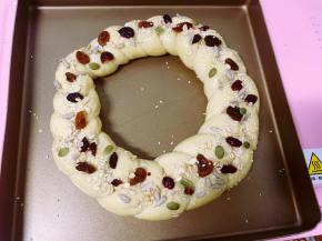 接着在面包胚的表面刷上薄薄的一层蛋液，然后撒上坚果仁、葡萄干和蔓越莓干做装饰。