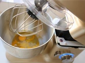 先来制作杯子蛋糕，把鸡蛋打散，和白砂糖，蜂蜜一起放入打蛋盆里。打蛋盆坐在40度左右的热水里，不停的搅拌蛋液，使蛋液整体达到温热的程度后拿出来，安装在厨师机底座上。开7档，大约打发时间需要4分钟。