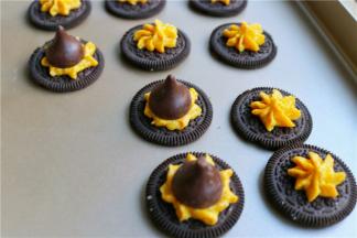 先来做帽子。奥利奥分开，夹馅可以不去，正面向上，挤上一点南瓜乳酪霜，放上一个好时巧克力。帽子就做好了。