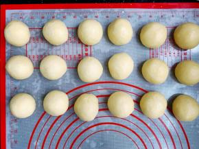 将发酵好的面团轻拍排气，然后滚圆，称重后分成均等的18个小面团，滚圆后盖上保鲜膜松弛10分钟。