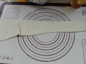 用擀面杖将其擀成一端窄一端宽的面片，同时在面片上面抹上适量食用油，涂抹均匀