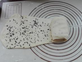 从窄的一端折叠卷起来，边折叠边拉伸。