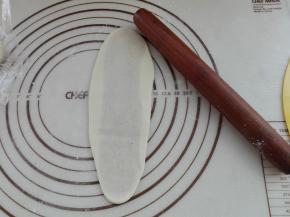 用擀面杖将其擀成一个长条，如图所示。