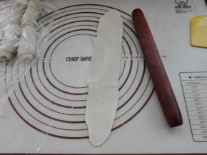 将卷过一次的小面卷，再次用擀面杖将其擀成长条，如图所示。