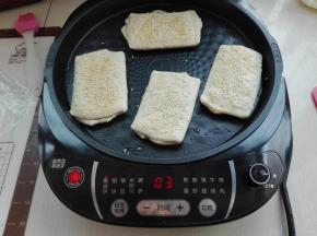 电饼铛刷上一层食用油，预热好后，将醒发好的面胚表面刷层水，沾上芝麻，将其烙制作两面金黄色即可。