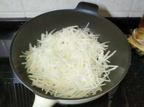 锅裏热油，放入萝蔔丝、糖，中火炒至软透有水溢出状态