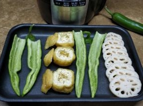 油豆腐剪开盖，用手指在白色部位挖开洞；尖椒对半切开，挖掉籽；莲藕切片备用
