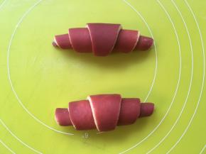 将三角形翻个面，红色部分朝下，之后从宽的一头轻轻卷起来，卷的时候力度一定要轻，不要太紧，会影响面团膨胀的，之后将卷好的牛角放入模具内室温发酵40分钟，剩下的边角可以扭成花朵一起放入模具内发酵 
