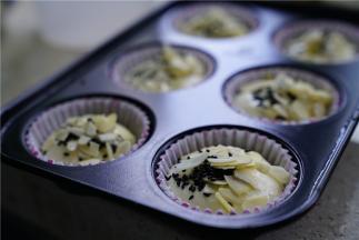 然后将蛋糕糊挤在纸托里，再用杏仁片及熟芝麻点缀。